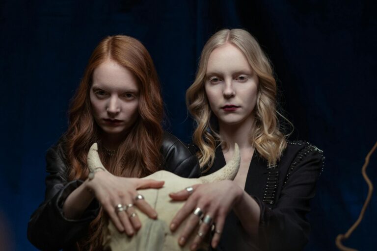 Two women engaged in mystical activities with a skull, exuding an aura of mystery and occult.